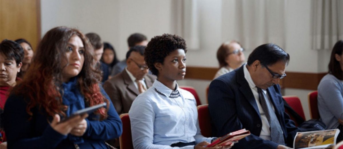 Members of The Church of Jesus Christ of Latter-day Saints attending sacrament meeting, sitting in pews in a chapel.